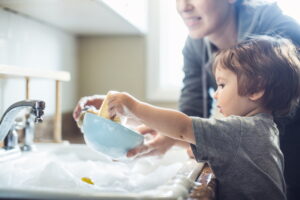 parent-and-toddler-washing-dishes-in-the-kitchen-sink